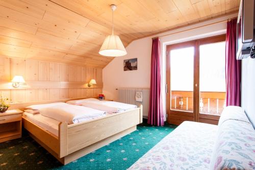 a bedroom with two beds and a large window at Gasthof Tuscherhof in Braies