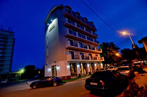 un edificio alto con macchine parcheggiate di fronte di Lucas Boutique Hotel a Eforie Nord