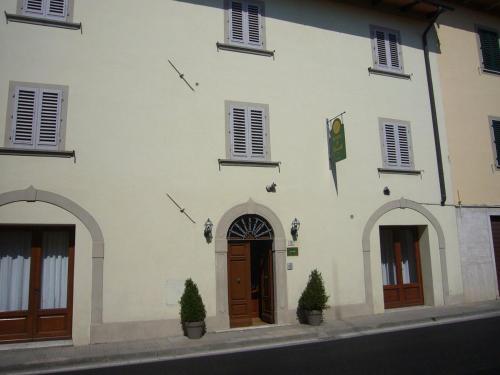 ein weißes Gebäude mit einer Tür und drei Fenstern in der Unterkunft Hotel Il Cavallo in Barberino di Mugello