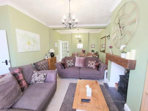 uma sala de estar com dois sofás roxos e uma mesa em The Bridge Cottage em Llanrwst