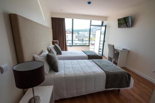 a hotel room with two beds and a window at Hotel Quinta do Viso in Miranda do Corvo