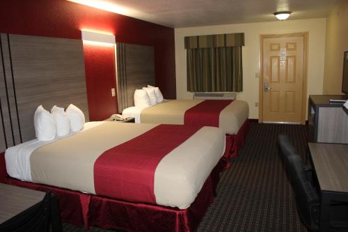 a hotel room with two beds and a desk at Scottish Inns Fort Worth in Fort Worth