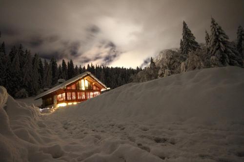 マドンナ・ディ・カンピリオにあるPra de la Casaの夜の雪の中のログキャビン