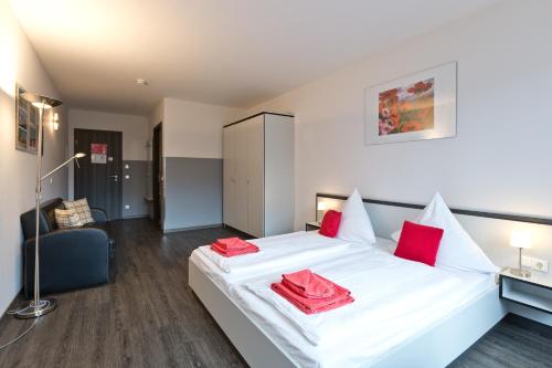 a bedroom with a white bed with red pillows on it at Hotel zwischen den Seen in Waren