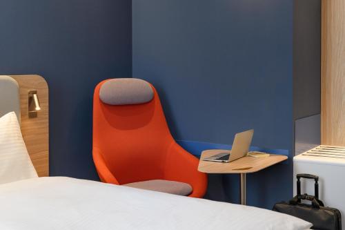 レーゲンスブルクにあるHoliday Inn Express - Regensburg, an IHG Hotelのベッド1台、椅子、ノートパソコンが備わる客室です。