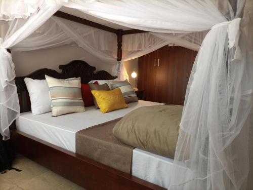 1 dormitorio con cama con dosel y muchas almohadas en AVISHAI HOMES, en Kisumu