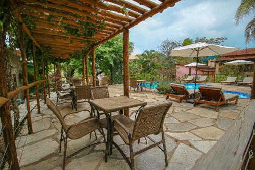 eine Terrasse mit Tischen und Stühlen und einem Pool in der Unterkunft Pousada Flores do Cerrado in Pirenópolis