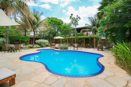 einen Pool im Garten mit Tischen und Stühlen in der Unterkunft Pousada Flores do Cerrado in Pirenópolis