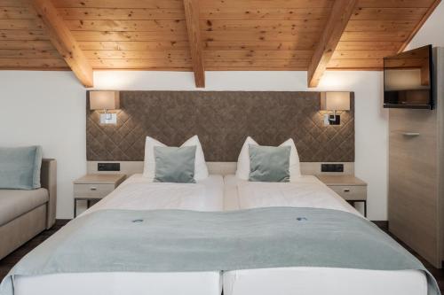 a bedroom with a large white bed and wooden ceilings at Hotel Garni Möwe am See in Prien am Chiemsee