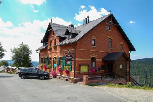 budynek z samochodem zaparkowanym przed nim w obiekcie Berggasthaus & Pension Schöne Aussicht w mieście Klingenthal