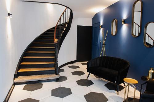 eine Treppe in einem Zimmer mit blauen Wänden und einem schwarzen Stuhl in der Unterkunft JAMES Résidence & Spa in Straßburg