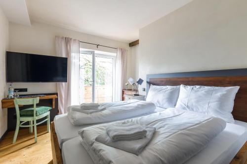 1 Schlafzimmer mit 2 Betten, einem Schreibtisch und einem TV in der Unterkunft Bergwirt Hotel & Gasthof in Kiefersfelden