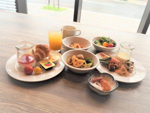 une table avec des assiettes de nourriture et des verres de jus d'orange dans l'établissement Quintessa Hotel Sapporo Susukino, à Sapporo