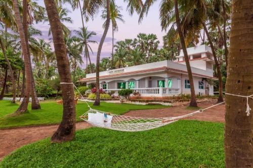 eine Hängematte vor einem Haus mit Palmen in der Unterkunft StayVista's Villa Bharat - Beachfront serenity with A spacious lawn in Mumbai