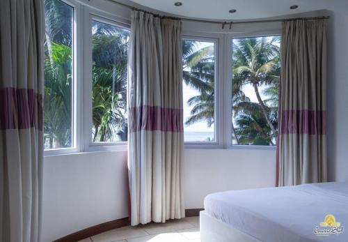 - une chambre avec un lit et 2 fenêtres avec des palmiers dans l'établissement Rosy Sea Front Beach Condo, à Bamburi