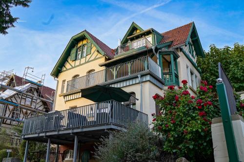 a yellow house with a balcony and an umbrella at Traumhaft wohnen in Jugendstilvilla in Speyer