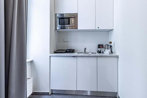 una cucina bianca con lavandino e forno a microonde di The Levante Rathaus Apartments a Vienna