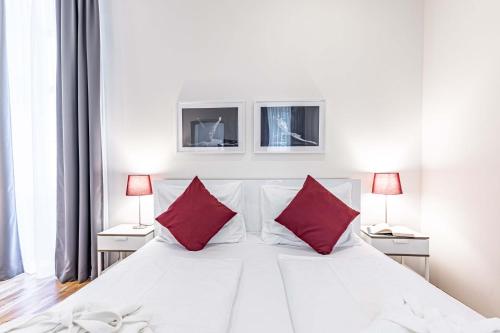 una camera da letto con un letto bianco con cuscini rossi di The Levante Rathaus Apartments a Vienna