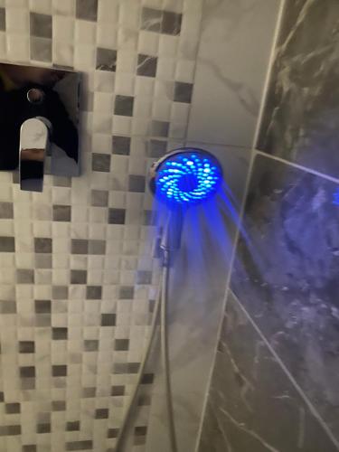 La salle de bains est pourvue d'un pommeau de douche avec une lumière bleue. dans l'établissement Apartman Royal, à Slavonski Brod