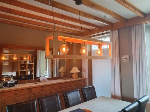 a dining room with a table and a chandelier at Gîte du Soleil in Anhée