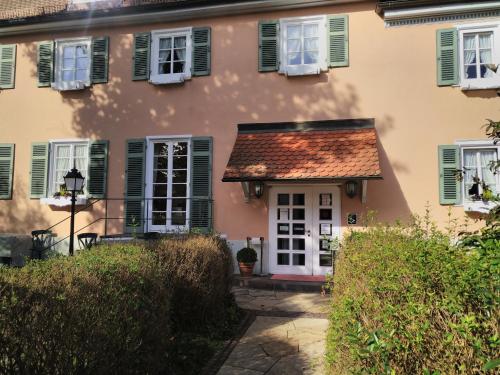 ein Haus mit rotem Dach und grünen Rollläden in der Unterkunft Landhotel Hirsch in Tübingen