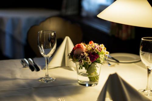 einen Tisch mit einer Vase aus Blumen und Weingläsern in der Unterkunft Landhotel Hirsch in Tübingen