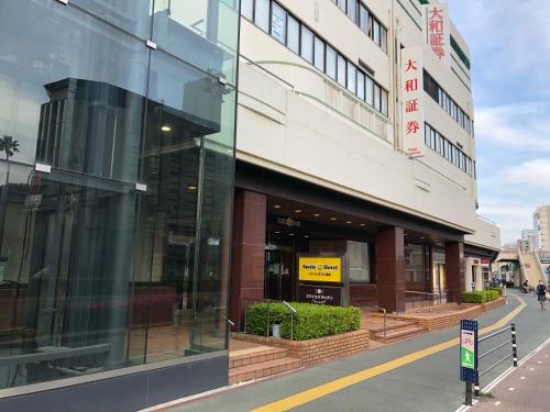 ein Gebäude mit Glasfenstern auf einer Stadtstraße in der Unterkunft Smile Hotel Tokushima in Tokushima