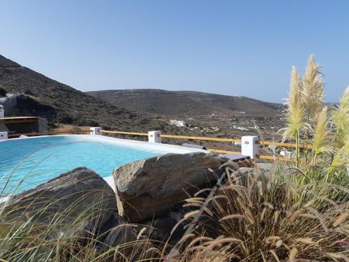 a swimming pool with rocks next to a mountain at 3 Paros *All Season* Villas in Parikia