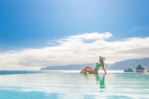 Eine Frau sitzt im Wasser in einem Infinity-Pool. in der Unterkunft Aqua Natura Bay in Porto Moniz