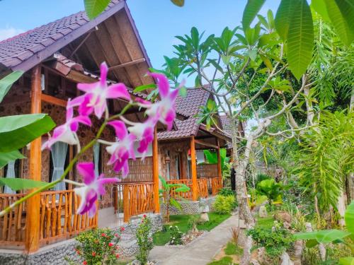 uma casa com flores cor-de-rosa em frente em Grealeen Cottages em Nusa Penida