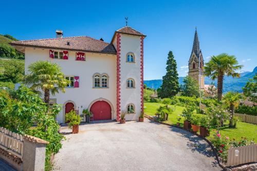 una grande casa bianca con una chiesa sullo sfondo di Überbacherhof a Termeno