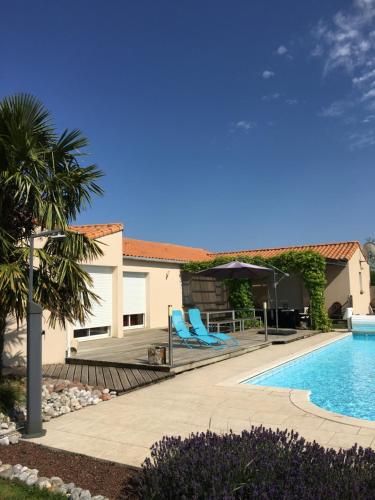 - une piscine avec des chaises longues bleues à côté d'une maison dans l'établissement La Chambre des Amis, à Parthenay