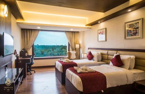 a hotel room with two beds and a television at KPM TRIPENTA HOTEL in Kozhikode