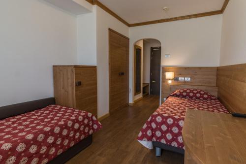 een hotelkamer met 2 bedden en een tafel bij Hotel Villa Argentina in Cortina dʼAmpezzo