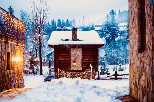 uma cabana de madeira na neve com luzes de Natal em KLEN Family em Mykulychyn