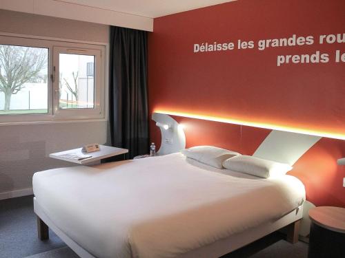 sypialnia z dużym łóżkiem i czerwoną ścianą w obiekcie ibis Styles Beauvais w Beauvais