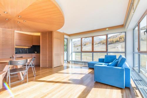 a living room with a blue couch and a kitchen at Terrazza su Sestriere Lux in Sestriere