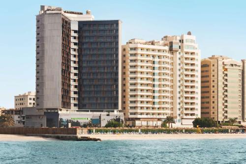 un gruppo di edifici alti vicino a una spiaggia di Wyndham Garden Ajman Corniche ad Ajman