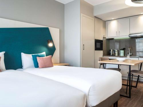 um quarto de hotel com uma cama grande e uma cozinha em Aparthotel Adagio Paris Suresnes Longchamp em Suresnes