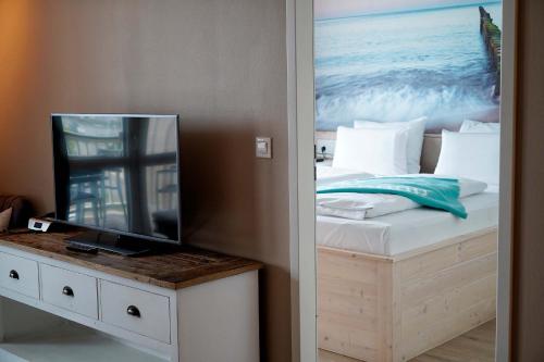 Schlafzimmer mit einem Bett und einem Flachbild-TV in der Unterkunft Beach Apartments Heiligenhafen in Heiligenhafen