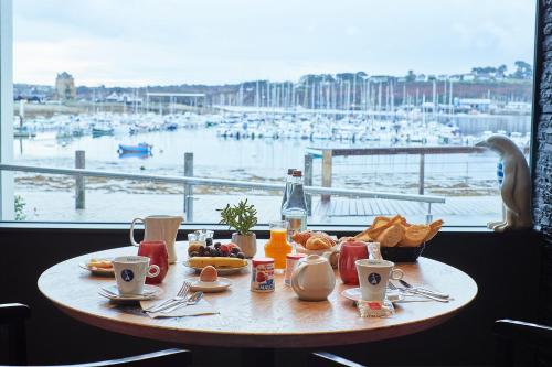 a table with breakfast food and a view of a harbor at Le Thalassa Hôtel & Spa in Camaret-sur-Mer