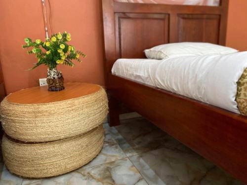 um quarto com uma cama e uma mesa com um vaso de flores em Gorilla African Guest House em Entebbe