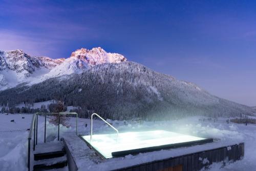 een hot tub in de sneeuw voor een berg bij Paramount Alma Suites in Sesto