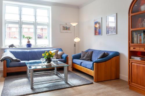 una sala de estar con 2 sofás azules y una mesa. en Stadthaus Jürgensby, en Flensburg