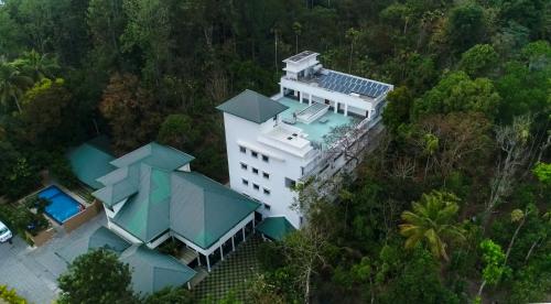 Cette chambre offre une vue sur un bâtiment blanc doté d'une piscine. dans l'établissement Peppervine Hotel, à Thekkady