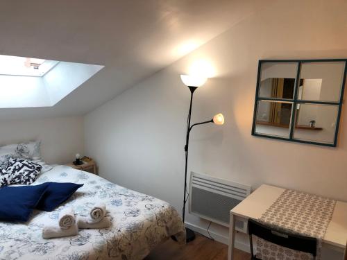 um quarto com uma cama, um candeeiro e uma secretária em Studio La Belle Vie em Suresnes