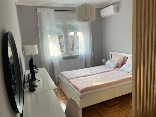 een slaapkamer met een bed en een bureau met een televisie bij Apartmani Sombor in Sombor