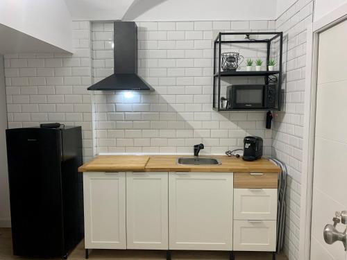 uma cozinha com um lavatório e um frigorífico preto em PUERTA DE CACERES Apartamento 2 em Cáceres