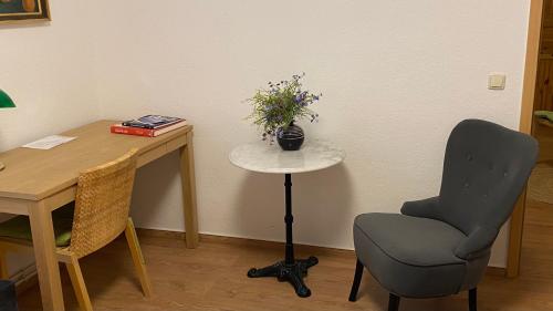 un escritorio con una silla y una mesa con un jarrón de flores en Ferienwohnung Zentrum, en Neuruppin