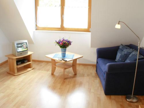 ein Wohnzimmer mit einem blauen Sofa und einem Tisch mit Blumen in der Unterkunft Apartment Dieboldshof by Interhome in Neuried